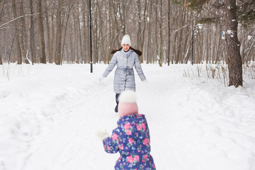 Family, children and nature concept - Mother with daughter have fun in the winter park