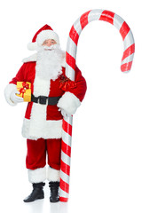 santa claus standing with big candy cane and christmas gift isolated on white