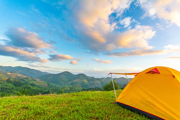 Camping orange tent on the mountain during sunrise in Chiang Rai, Thailand.