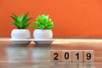 Cube number 2019 and plant tree on cement on amber background, happy new year concept and save the earth idea