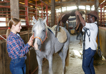 Farm workers preparing horse harness