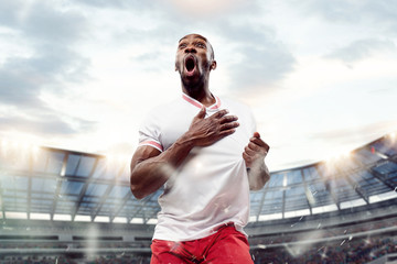 The football african player in motion on the field of stadium at day. The professional football,...