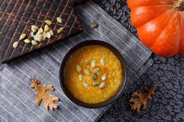 Pumpkin soup with pumpkin seed on dark background.