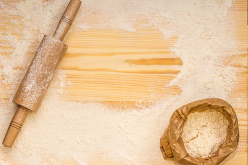 Flour and rolling-pin for dough on a wooden board. Baking background.