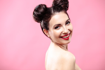 Beauty portrait of young brunette woman on a bright pink background. Model with make-up and hairstyle, closeup, fashion glamour photo