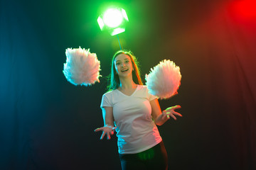Cheerleading young woman dancing with pom-poms on colourful background © satura_