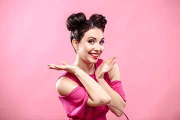 Beauty portrait of young brunette woman on a bright pink background. Model with make-up and hairstyle, closeup, fashion glamour photo