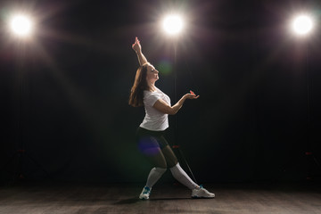 Dance, hip-hop, jazz funk and people concept - flexible young woman dancing in the darkness under the light
