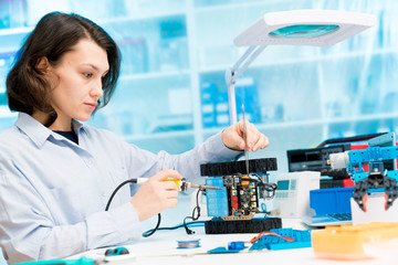 Student girl in electronics laboratory, experiment with microcontroller and robot cnc module