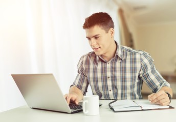 Happy young man works on his laptop