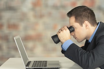 Man searching in laptop. with binoculars