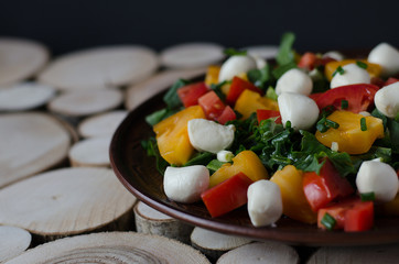 Salad with mozzarella on wooden background.