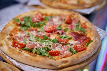 Spicy Pizza with Salami, Mozzarella, tomatoes, arugula and Tomato Sauce. Italian pizza.