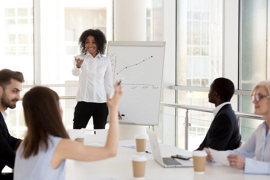 Smiling African American female mentor or coach training employees in office, interacting with workers asking questions, black woman give flipchart presentation for company interns teaching business