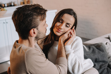 smiling tender couple cuddling on couch at home