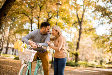Naklejka na ściany i meble Active senior couple together enjoying romantic walk with bicycle in golden autumn park