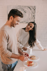 beautiful young couple with pancakes with jam for breakfast at home