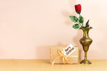 red rose flower in east gold antique brass vase, and box gift with merry christmas card 