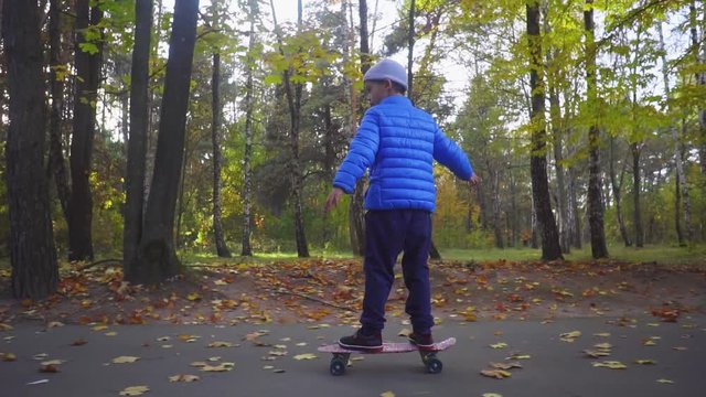 Skateboarder boy child ride on skate outdoor in autumn park