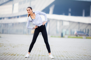 Fitness woman doing workout standing in a stadium background