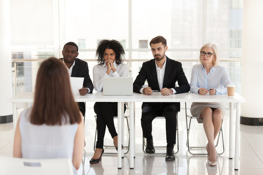 Diverse HR managers listen to female job candidate speaking during work interview in office, multiethnic recruiters consider woman candidature at hiring. Recruitment, employment concept