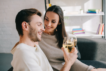 beautiful young couple drinking wine on couch at home