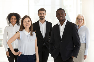 Portrait of happy diverse work team standing looking at camera motivated for success and new achievements, smiling multiethnic managers or workers feel excited posing in office together
