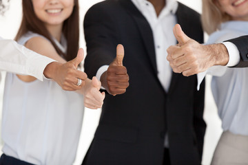 Close up of multiethnic happy workers or employees show thumbs up sign satisfied with career or company choice, smiling diverse business clients or customers gesture great positive experience