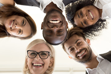 Low angle shot of smiling diverse office employee looking at camera hugging happy with career...
