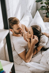 high angle view of happy young couple relaxing and chatting in bed in morning