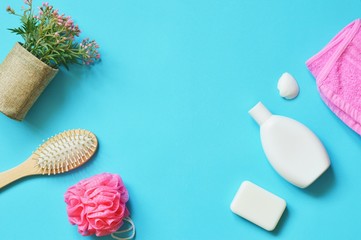 Flat lay bath products. Organic shampoo, soap bar, hair brush, pink towel and flowers