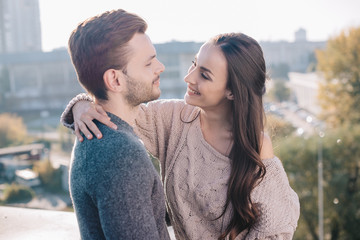 happy young couple embracing and looking at each other on rooftop
