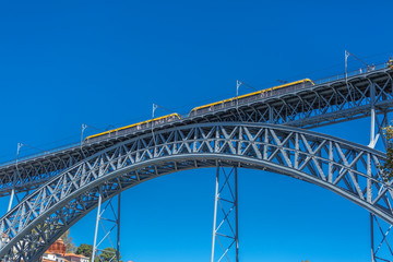 Fototapeta na wymiar View of the metallic bridge of D. Maria Pia, built by Gustave Eiffel, with yellow subway wagon, in Porto