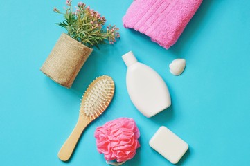 Flat lay bath products, bathroom stuff. Flowers, pink towel, shampoo bottle, soap, sponge and hair brush