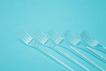 Plastic cutlery forks arranged on a blue background. Plastic waste problem