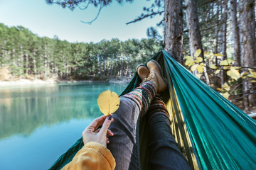 Woman relaxing in the hammock by the lake - obrazy, fototapety, plakaty
