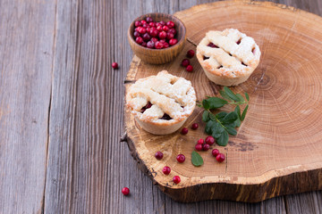 Homemade tartlet with cranberries on wooden table.