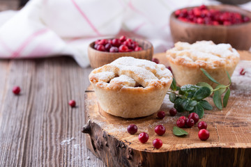 Homemade tartlet with cranberries on wooden table.