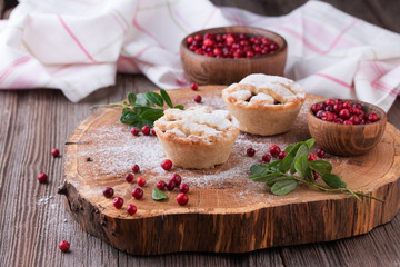 Homemade tartlet with cranberries on wooden table.