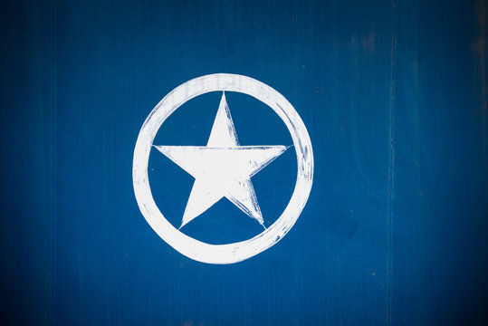 a white star in a white circle painted on a metallic blue background