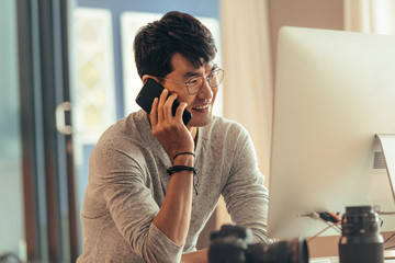 Photo editor talking on phone at his workdesk