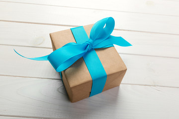 recycled paper gift box with Blue ribbon on old wooden white background.Top view
