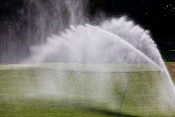Sprinkler system working on fresh green grass on football (soccer) stadium
