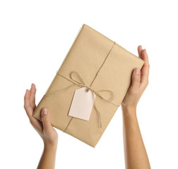 Woman holding parcel wrapped in kraft paper on white background, closeup