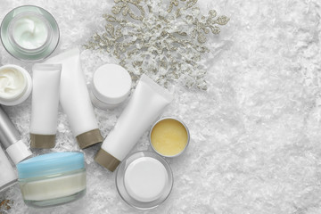 Fototapeta na wymiar Set of cosmetic products on decorative snow, flat lay with space for text. Winter care