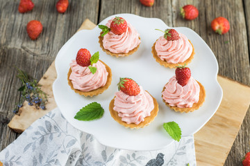 Top view of a Strawberry tarts with strawberry whipped cream on white plate.