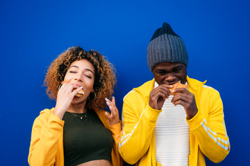 Young couple eating burger outdoors © karrastock