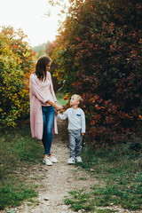 Happy family on autumn walk! Mother and son walking in the Park and enjoying the beautiful autumn nature.