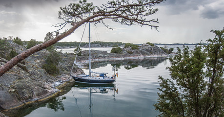 Sailboat at anchor in a lonely bay of Gubboe Kupa Skerry island in the Stockholm skerry gardenm...