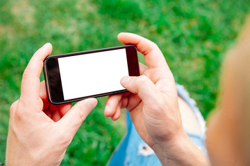Man using smartphone with blank screen outdoors, closeup. Mock up for design